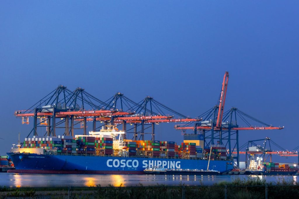 A COSCO shipping cargo vessel docked at Maasvlakte port, illuminated against the night sky in Rotterdam.